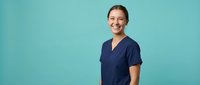 Happy female healthcare worker in navy blue medical scrubs smiling confidently against turquoise background for medical and wellness industry marketing.