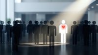 Illuminated figure with glowing heart stands out among crowd of silhouettes in modern office space, representing leadership, empathy and human connection in workplace.