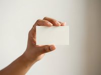 Male hand holding blank white business card against neutral background, ready for branding and corporate identity design projects.
