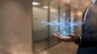 Businessman holding glowing digital network connections with data particles floating above palm in modern office environment for technology presentations.