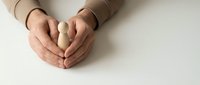 Hands clasped together in prayer or meditation position on white surface, showing peaceful gesture and mindfulness practice for wellness concepts.