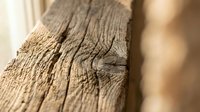 Weathered wooden beam with deep natural cracks and grain texture showing age and character for rustic interior design and construction projects.
