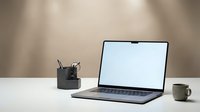 Modern laptop computer with blank white screen on clean desk workspace with coffee cup and office supplies for business productivity.