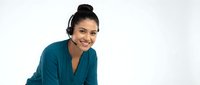 Professional Asian businesswoman with headset smiling during video call or customer service work in modern office environment for corporate communications.