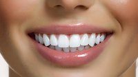 Close up of bright white healthy teeth and natural pink lips showing perfect dental care and oral hygiene against neutral background.