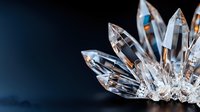 Sparkling clear crystal quartz points cluster against dark background, macro photography shows faceted surfaces catching light and creating prismatic reflections.