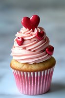 Valentine's Day cupcake with pink frosting and red heart decorations on top for romantic celebration and love-themed dessert concepts.