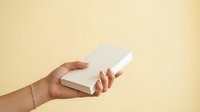Hand holding white box on beige background for product packaging mockup, branding, retail display, and commercial advertising purposes.