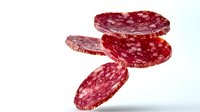 Sliced salami sausage with white fat inclusions on white background, isolated for food packaging design and menu illustrations.