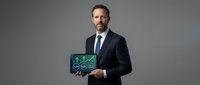 Caucasian male professional in formal business attire holding tablet displaying green network icons, representing digital connectivity and corporate technology solutions for enterprise applications.