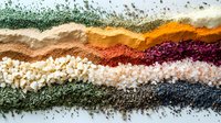 Colorful spices and seasonings arranged in wavy lines creating abstract food art pattern, vibrant cooking ingredients on white background for culinary designs.