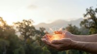 Hands cupping glowing light burst with starburst effect against mountain landscape at golden hour sunset for spiritual energy and hope concepts.