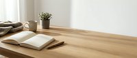 Wooden desk with open notebook, coffee mug, potted plant and folded fabric, minimalist workspace setup for home office or creative work.