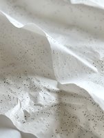 Creamy white meringue texture with tiny black vanilla seeds scattered throughout creates soft peaks and waves, capturing light and shadow in delicate folds.
