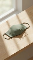 Green fabric face mask on a wooden surface with Stay Safe text in warm sunlight, symbolizing health protection and safety awareness.