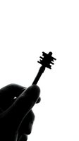 Hand holding small black silhouette key against white background. Minimalist concept for security, access, solutions and unlocking potential.