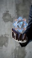 Hand holding glowing neon geometric mandala symbol with blue and orange light against weathered concrete wall background for technology and innovation concepts.