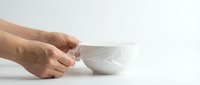 Person holding white ceramic bowl on white background, isolated for design and product mockup use.