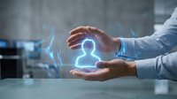 Businessman hands protecting glowing human figure icon with digital network connections. Corporate security, employee protection and human resources concept.