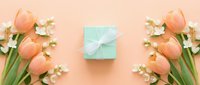 Spring tulips and jasmine flowers with mint gift box on coral background for Mother's Day celebration and romantic occasions.