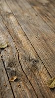Weathered wooden planks with natural grain texture and scattered autumn leaves, suitable for backgrounds, flooring design, and rustic interior projects.