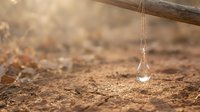 Water drop falling onto dry cracked earth soil during drought, representing water scarcity, environmental crisis, and climate change impact on agriculture and natural resources.