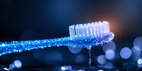 Wet toothbrush with water drops and bokeh lights in dark blue background creates fresh clean dental hygiene concept for oral care and health promotion.
