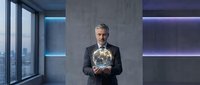 Mature Caucasian businessman in dark suit holding glowing Earth globe in modern office with concrete walls and purple lighting for global business concepts.