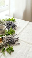 Fresh lavender bundles and mint leaves arranged on white linen fabric near bright window for natural aromatherapy and herbal wellness applications.