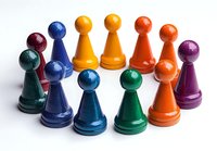 Colorful wooden game pieces arranged in circle on white background. Board game pawns in rainbow colors for family entertainment and strategic play.