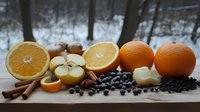 Fresh winter fruits and spices arranged on wooden board with snowy forest background, oranges, apples, blueberries and cinnamon sticks in rustic setting.