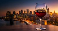 Glass of red wine on table overlooking city skyline at sunset with warm golden light creating romantic urban dining atmosphere for luxury lifestyle concepts.