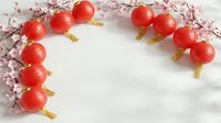 Red paper lanterns with golden tassels and cherry blossom branches create festive Asian celebration frame on white marble background for holidays.