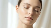 Young Caucasian woman with closed eyes and natural makeup showcasing healthy glowing skin in soft natural light for skincare and beauty concepts.