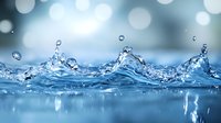 Dynamic water splash with crystal clear droplets creating a crown-like formation against soft blue bokeh background, capturing motion and purity in nature.