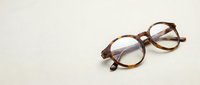 Pair of tortoiseshell-framed eyeglasses with clear lenses resting on neutral background, suitable for optometry, vision care, eyewear retail, and healthcare marketing.