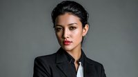 Professional Asian businesswoman in black suit jacket with confident expression against gray background for corporate and business presentations.