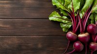 Fresh organic beetroots with green leaves on dark wooden background, top view with copy space. Natural healthy vegetable composition for food design.