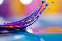 Dynamic splash of vibrant purple liquid with floating droplets against colorful orange and blue background, captured in macro photography with creative lighting effects.
