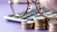 Financial planning concept with eyeglasses and stacked coins on documents representing investment strategy and money management for business growth.