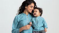 Young Indian mother in traditional turquoise kurta holding smiling toddler daughter in matching ethnic outfit, expressing love and bonding on white background.