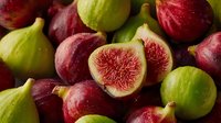 Fresh ripe figs with green and purple skin showing sweet red flesh interior. Organic Mediterranean fruit harvest for healthy eating and gourmet cooking.