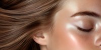 Close up view of young woman with closed eyes, glowing healthy skin and flowing brown hair against neutral background. Professional beauty and skincare concept.