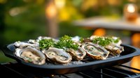 Fresh oysters on half shell garnished with herbs served on black plate outdoors with blurred natural background. Perfect for seafood restaurant menus.