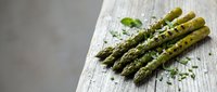 Fresh green asparagus spears with herbs on rustic wooden board, healthy organic vegetable ingredient for cooking and culinary preparations.
