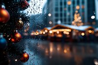 Raindrops on window with blurred Christmas market and decorated tree in foreground, creating atmospheric evening cityscape with glowing bokeh lights and festive ornaments.