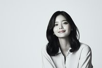 Young Asian woman with confident smile wearing white shirt against light background, natural makeup and black shoulder-length hair creating minimalist portrait.