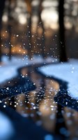 Magical winter forest reflection in puddle with falling snow and bokeh lights creating dreamy atmosphere at dusk, soft focus nature photography.