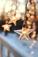 Glowing star-shaped string lights with warm bokeh background create magical holiday atmosphere, close-up view of illuminated Christmas decoration.