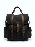 Vintage style canvas backpack with brown leather straps and buckles on white background, black fabric texture with multiple pockets for travel and everyday use.